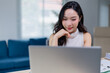 © Tj - Focused young woman engaging with her laptop in a bright office setting, exemplifying modern work culture and technology use in professional environments
