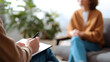 © Oksana_Latysheva - Psychotherapy session close-up. Close-up view of a therapist taking notes during a session with a blurred patient in the background. Ideal for mental health, support, and counseling themes.Keywords: