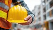 © Johannes - building, protective gear and people concept - close up of builder holding yellow hardhat or helmet at construction site, no logos, no brands