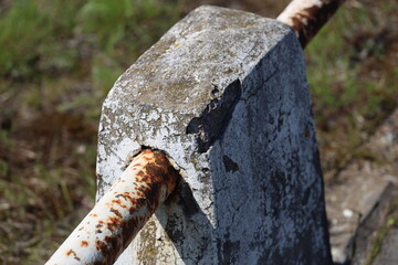 Poster - A rusty metal piece sits atop a gray cement block, withered and worn