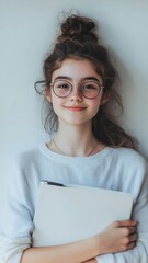 Poster - Portrait of a smiling student girl with hair tied up and wearing round eyeglasses, holding books against a white background, ready for school and eager to learn