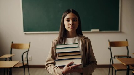Poster - Confident student holding a pile of books stands in a classroom, ready for the new school year, embodying the spirit of learning and academic pursuit