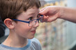 © Austockphoto - Young boy trying on different frames for new glasses