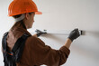 © Andrii Lysenko - Female builder measuring wall with spirit level while working on construction site or doing home renovation DIY
