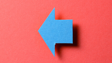 Poster - Blue blank paper cardboard arrow direction sign with shadow and copy space for text on red background, flat lay top view pointing symbol message backdrop