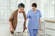 © Ekkasit A Siam - Senior asian female patient walking slowly with walker under supervision of female physiotherapist in blue uniform during recovery process inside rehabilitation center