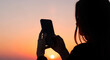 © Mairon - Silhouette of girl photographing sunset with smartphone, modern lifestyle and nature.