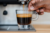 Espresso Pour: A close-up captures the rich dark espresso being extracted into a clear glass, held by a hand, revealing the drink's layers.
