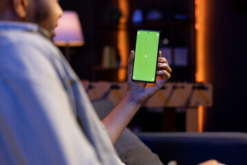 Poster - African american remote worker uses chroma key screen on gadget to work in the living room, sitting on the couch in his modern stylish living room. Happy young adult on the internet.