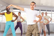 © JackF - European guy teaches sequences of movements, actions during dance lesson, trains to doing elements of RnB dance, enjoys active hobby to music. Multinational group rehearsal, dance choreography coach