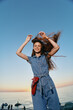 © SHOTPRIME STUDIO - lifestyle woman in modern boho-western denim outfit enjoys carefree moment by the sea with natural light and film color effect at sunset
