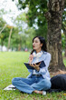 © David - Young studying students asian woman sitting outdoors and reading a book enjoying leisure time in a park,  copy space. Education studying students concept