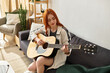 © Bliss - Enjoying music and creativity, a young woman plays guitar on a cozy afternoon at home