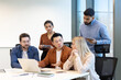 © Liubomir - A diverse team collaborates around a table, discussing a laptop and sharing ideas. The focus is on teamwork and problem-solving.