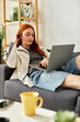 © Bliss - Young beautiful woman relaxing at home while working on her laptop in a cozy living room