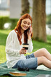 © Bliss - Young woman enjoys her spare time in the park while sipping coffee and chatting on the phone