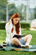 © Bliss - Young woman enjoying her spare time while reading and writing in a park on a sunny afternoon