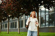 © Bliss - Young woman enjoying a sunny day in the park with a coffee in hand and a smile on her face