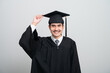 © PhugunStock - A young man in a graduation gown and cap smiles at the camera, striking a confident pose to celebrate his academic achievement on graduation day.