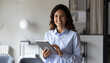 © decky - Portrait of young Hispanic professional business woman standing in office. Happy female company executive, smiling businesswoman entrepreneur corporate leader manager looking at camera using tablet.