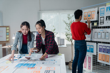 Poster - Creative team working on mobile app interface design, using wireframes and prototypes. Designers collaborating at a table, analyzing layouts and user experience elements