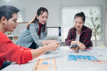 Fototapete - Young asian ux ui designers working on mobile app interface wireframe design at modern bright co-working space, creating modern user interface for smartphone