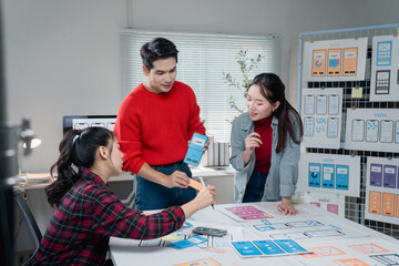 Fototapete - Diverse team of designers actively collaborates on a mobile app project, discussing user interface layouts and wireframes. They are focused on creating an intuitive and user-friendly experience