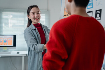 Fototapete - Two young web designers engaging in a discussion about user interface design while showcasing a new mobile application prototype in a modern office setting