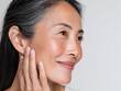 © Andini - 50s middle aged old woman looking at camera isolated on white background advertising dry skin care treatment anti age skincare beauty, plastic surgery, cosmetology procedures. Close up half face view