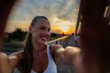 © DusanJelicic - Sporty woman capturing a joyful selfie on a bridge during a stunning sunset after her workout, celebrating her commitment to a healthy lifestyle and fitness journey
