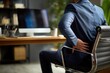 © ttonaorh - A man with back pain at work, sitting in front of a computer on a chair and holding his lower back. The home office interior serves as the background.