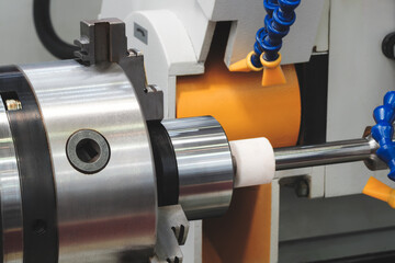 Poster - Industrial sharpening machine with large abrasive white disc sharpening round metal part, industrial concept background.