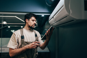 Poster - Technician performs maintenance on air conditioning unit while checking data on tablet