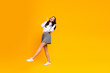 © deagreez - Cheerful young woman in stylish outfit posing lively on vibrant yellow background expressing charm and positivity