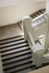 Poster - A stunning staircase is illuminated by natural light, featuring a mix of modern and classic elements, creating an inviting atmosphere in a spacious area.