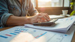 © Oran - Efficiently working on financial reports, person uses calculator amidst documents and charts, showcasing productivity and focus