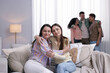 © New Africa - Friends hugging on sofa indoors, selective focus