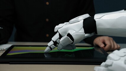 Poster - A close-up of a robotic hand interacting with a digital screen, showcasing data trends in a modern workspace, highlighting the fusion of technology and business analytics.Noogenesis