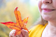 © kittyfly - Happy middle-aged woman with autumn yellow leaf celebrating nature, fall season, enjoying fresh air, outdoor portrait, positive energy, nature background