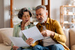 © Home-stock - Elderly spouses checking financial documents, calculating family budget, sitting on couch in living room at home