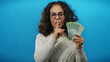 © Krakenimages.com - Woman holding ruble banknotes on blue background conveying secrecy with finger gesture, suggesting confidentiality or financial secrets in a visually striking isolated scene.