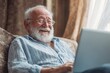 © Popelniushka - Joyful Elderly Man Gesticulating with Laughter While Engaged with His Laptop at Home