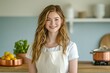 © imagepocket - A smiling young woman wearing an apron in a kitchen setting.