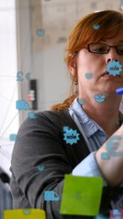 Poster - Animation of connected icons over caucasian businesswoman writing on sticky note on glass wall