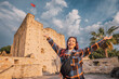 © EdNurg - Young woman with open arms enjoying freedom in front of an ancient castle with Turkish flag waving in the background