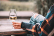 © EdNurg - Woman holding glass of chilled white wine sitting at wooden table enjoying relaxing day in the countryside