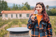 © EdNurg - Woman grimacing while drinking a glass of bad white wine in a vineyard with a farmhouse in the background