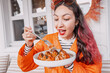 © EdNurg - Happy young woman with pink hair streaks enjoying delicious dumplings on a cozy terrace, savoring every bite of her tasty meal