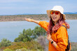 © EdNurg - Young woman birdwatcher enjoying summer holidays, pointing at a stunning landscape with a cheerful smile, embracing the beauty of nature and adventure