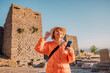 © EdNurg - Happy tourist visiting the ruins of Assos in Turkey and using smartphone app as audio guide